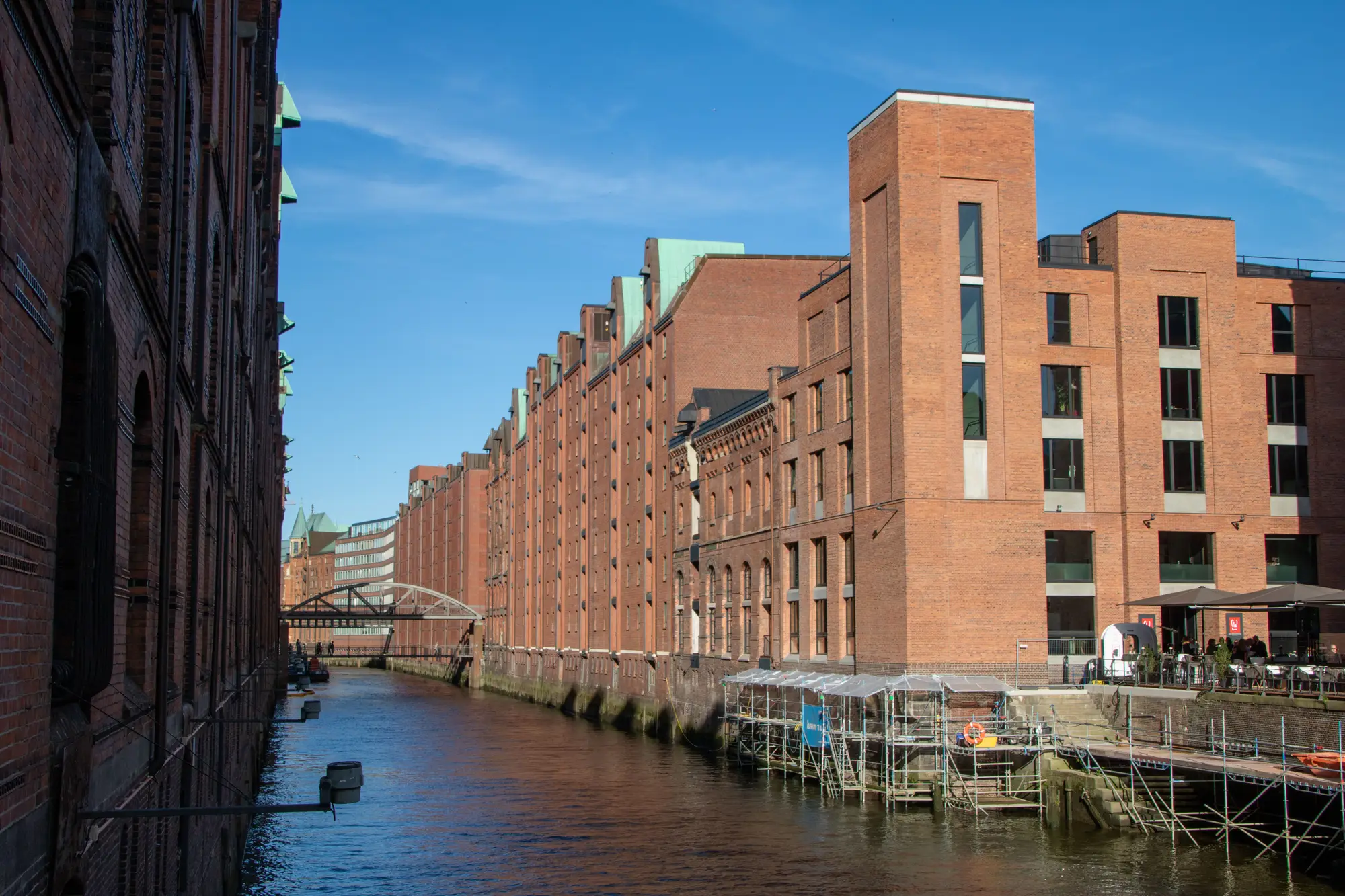 Red-brick warehouses of Hamburg's Speicherstadt along a canal on a sunny day.
