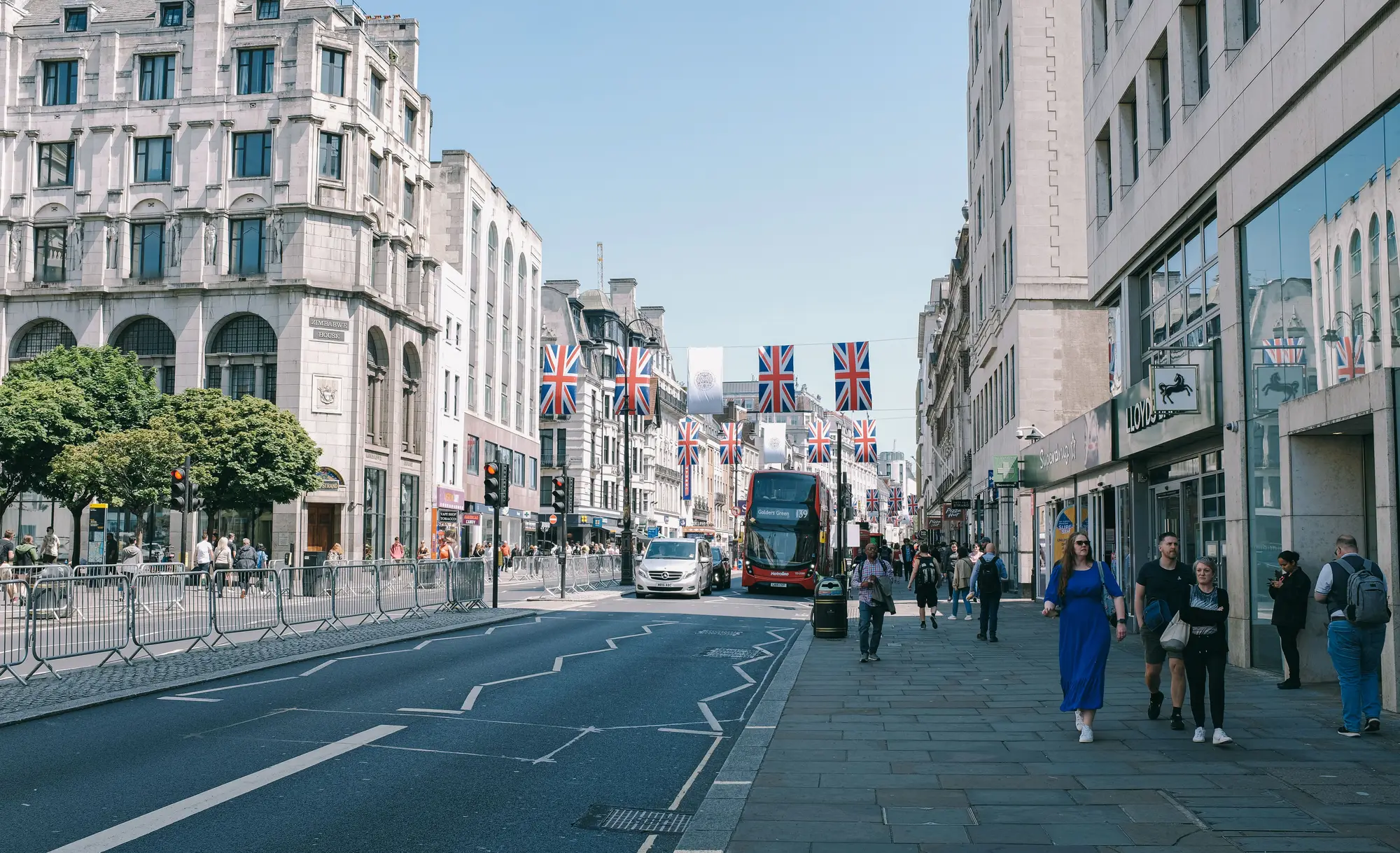 A London street hung with Union flags, with a red double-decker bus in the traffic.